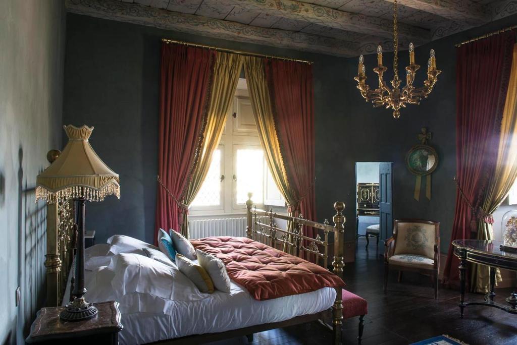 罗德兹卡纳克城堡住宿加早餐旅馆的一间卧室配有一张带红色窗帘和吊灯的床。