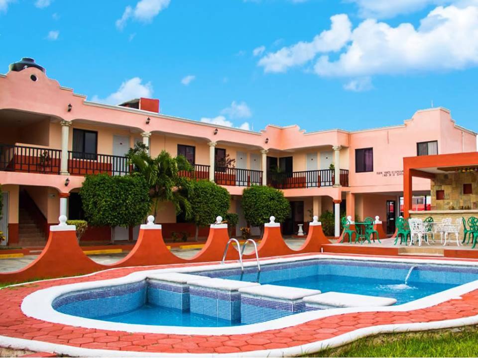 梅里达Hotel Hacienda Cortes的一座带游泳池的度假村,位于一座建筑前