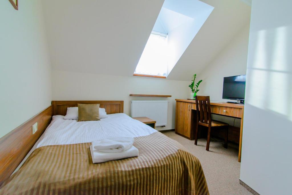 格涅兹诺诺克勒吉索班斯基齐旅馆的一间卧室配有一张带书桌和电视的床。