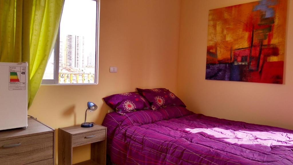 伊基克Iquique sun的一间卧室设有紫色的床和窗户