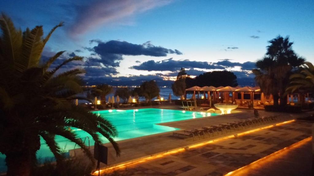 路特奇Ramada Loutraki Poseidon Resort的游泳池与度假村在晚上