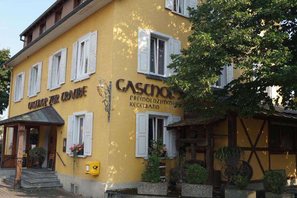 康斯坦茨Gasthof zur Traube的黄色的建筑,旁边标有标志