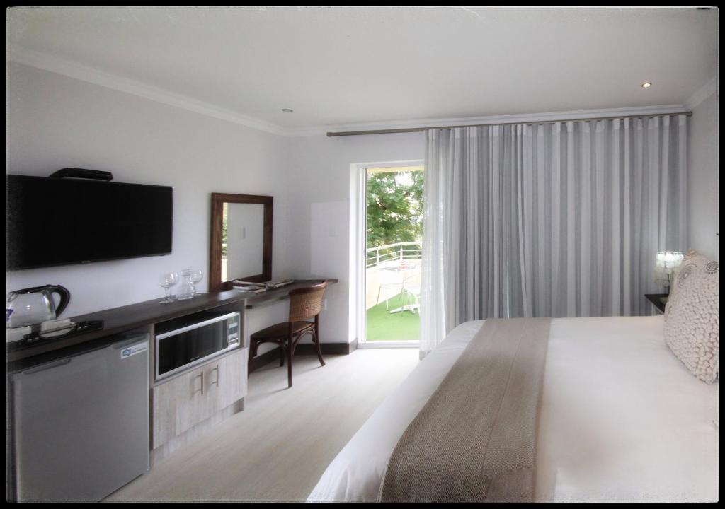 布隆方丹Impa-Lala Country Estate的一间卧室配有一张床、一张书桌和一台电视