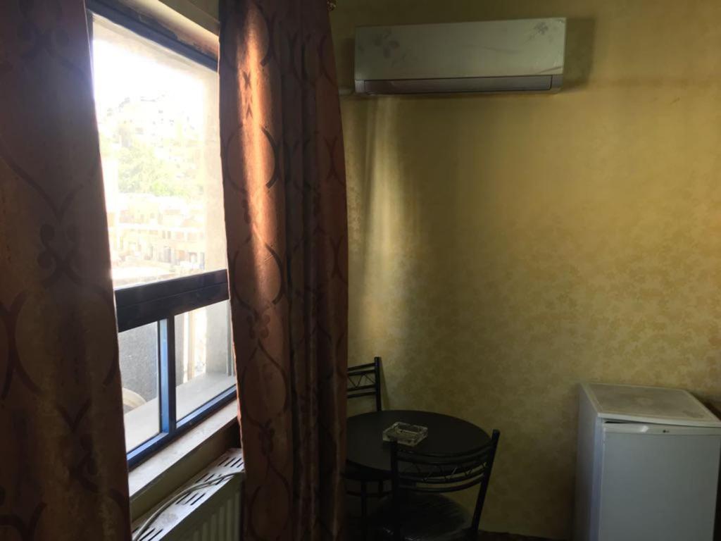 安曼亚洲大酒店的小房间设有窗户、桌子、桌子和椅子