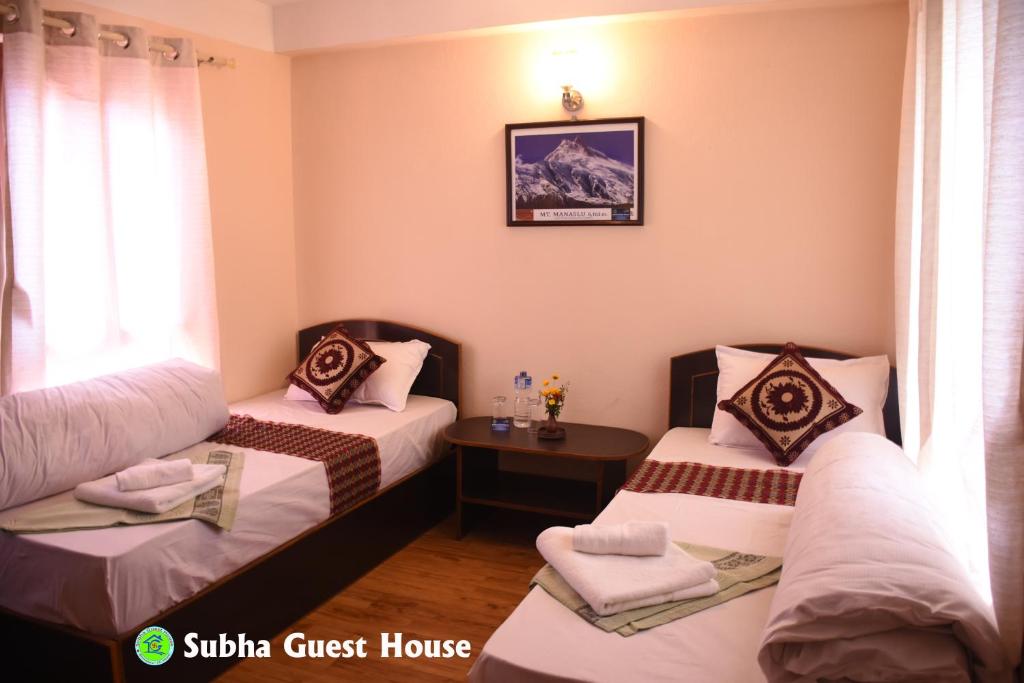 巴克塔普尔Subha Guest House的酒店客房设有两张床和一张桌子。