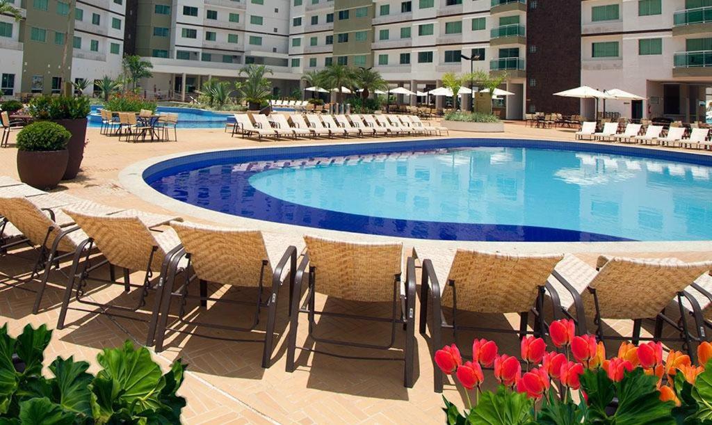 卡达斯诺瓦斯Riviera Park - Achei Ferias的酒店前方的游泳池设有椅子和鲜花