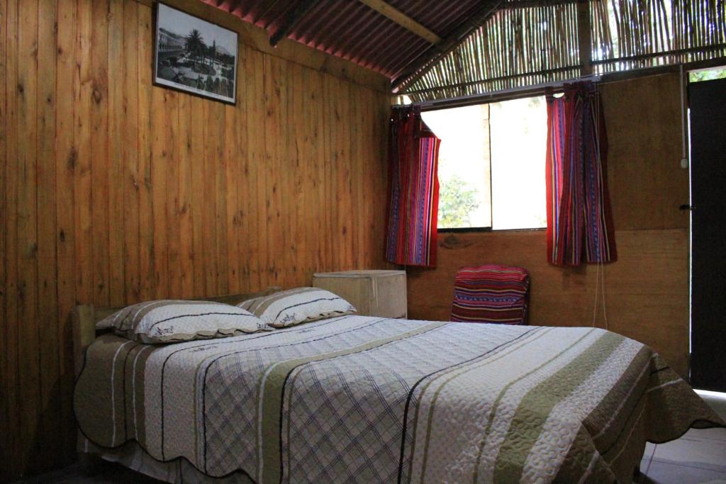 卡瓦纳科德Oasis Paraiso Ecolodge的卧室配有木墙内的一张床