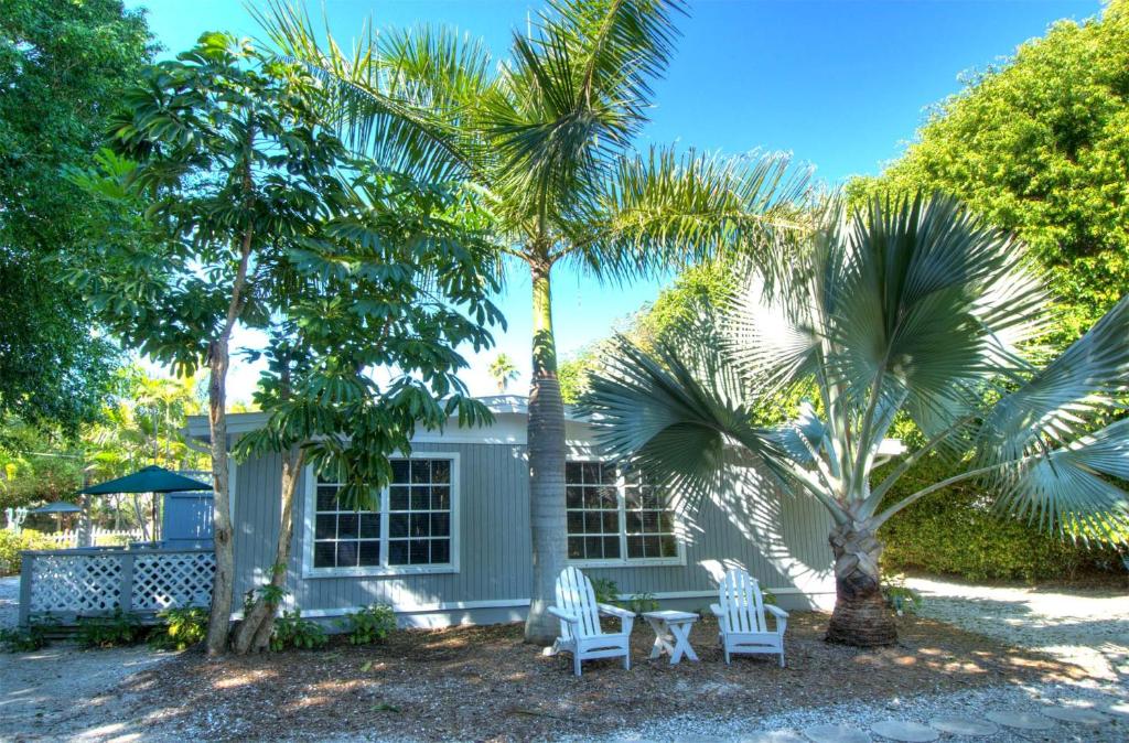 萨尼贝尔Seahorse Cottages - Adults Only的两棵棕榈树和桌椅的房子