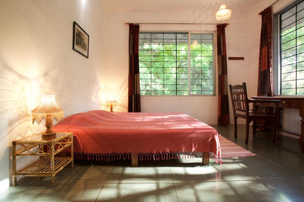 黎明之村The Annex, Isai Ambalam guest house的一间卧室设有红色的床和窗户。