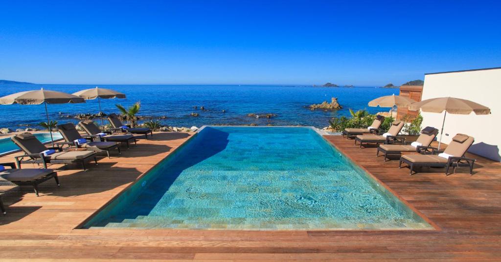 阿雅克修周末酒店的一个带椅子的游泳池,背景是大海