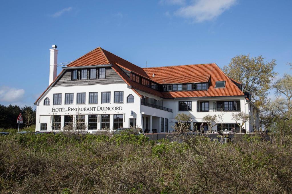 瓦瑟纳尔迪努尔德弗莱彻酒店 的一座白色的大建筑,有橙色的屋顶