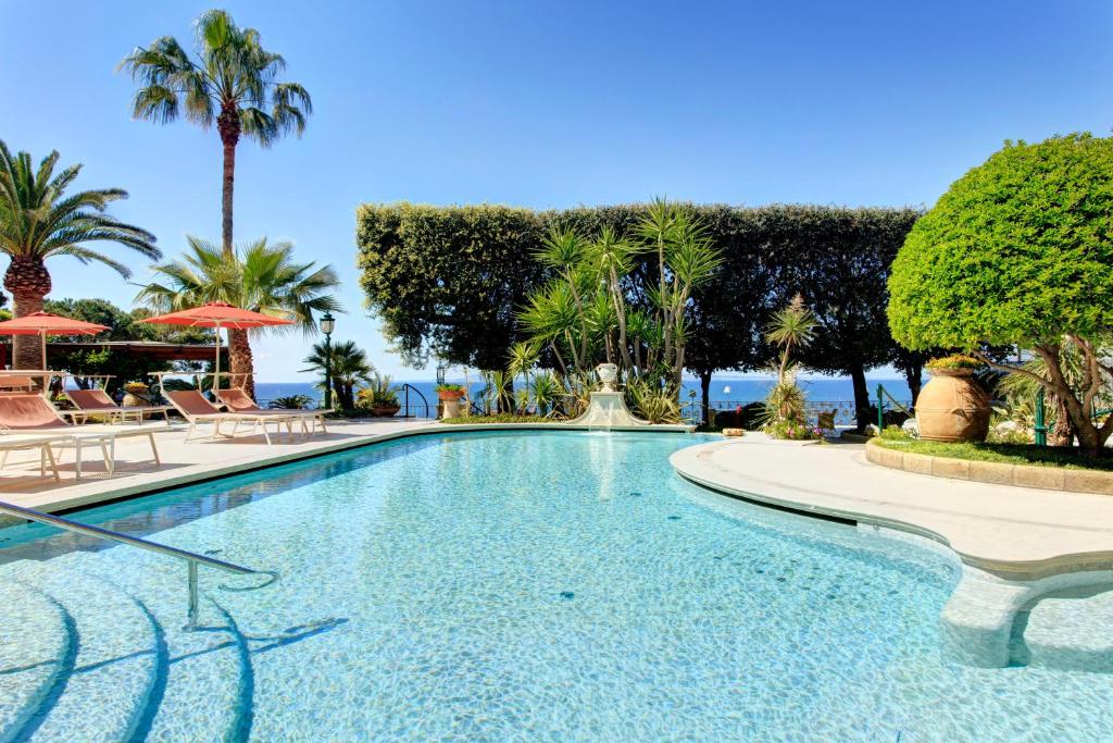 索伦托安巴夏托理大酒店的一个带椅子和棕榈树的游泳池以及大海