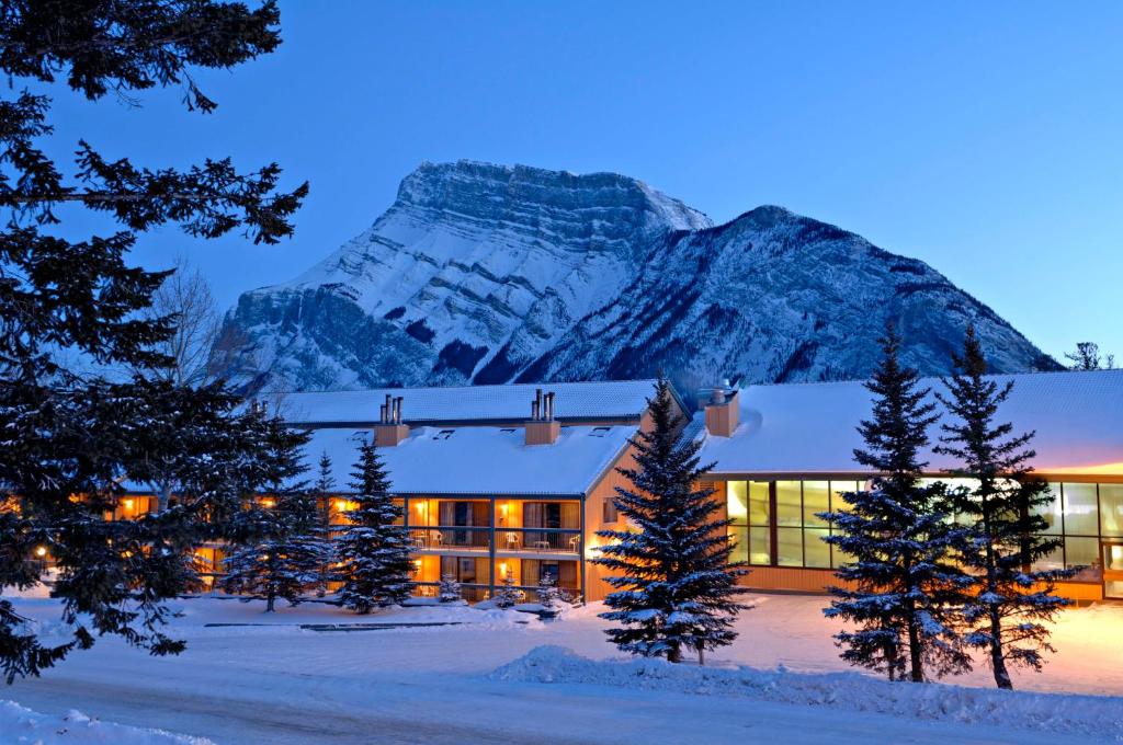 班夫花旗松小屋度假酒店的雪中酒店,背景是一座山