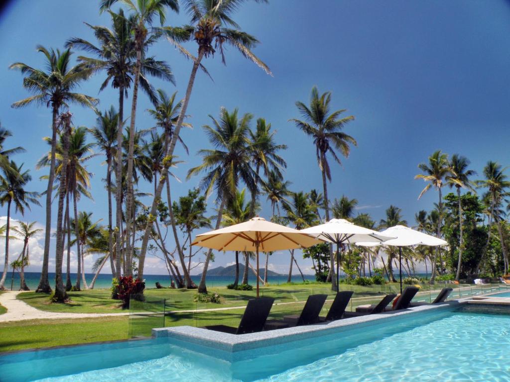米申海滩任务海滩漂流温泉度假酒店的海滩上的游泳池,种植了棕榈树和遮阳伞