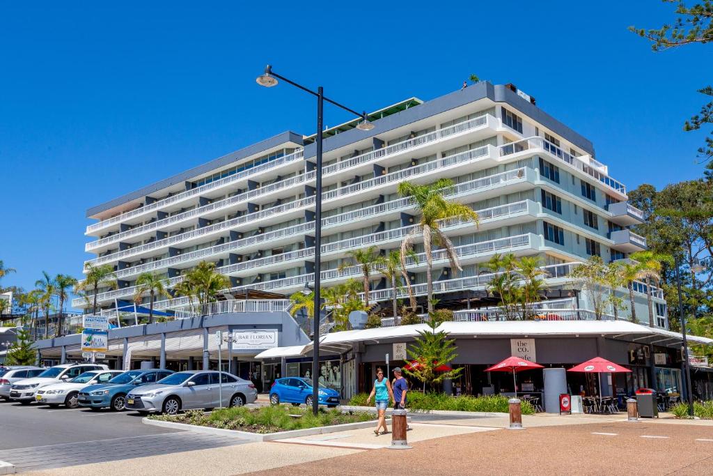 麦夸里港太平洋港度假酒店的停车场内停放汽车的大型建筑