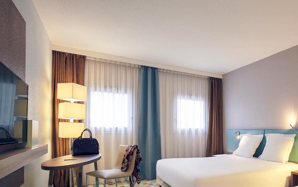 布西圣乔治马恩河谷布西圣乔治美居酒店的配有一张床、一张书桌和一扇窗户的酒店客房