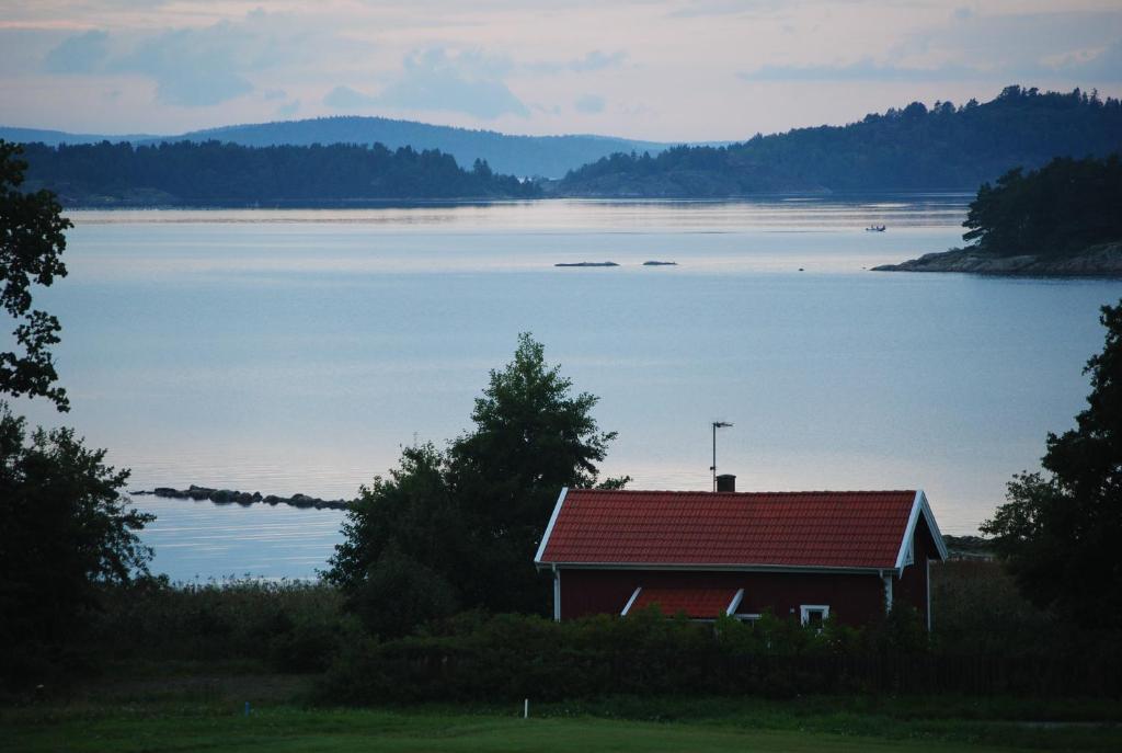 卢恩斯基尔Anfasteröd Gårdsvik - Sjöstugan的湖边有红色屋顶的房子