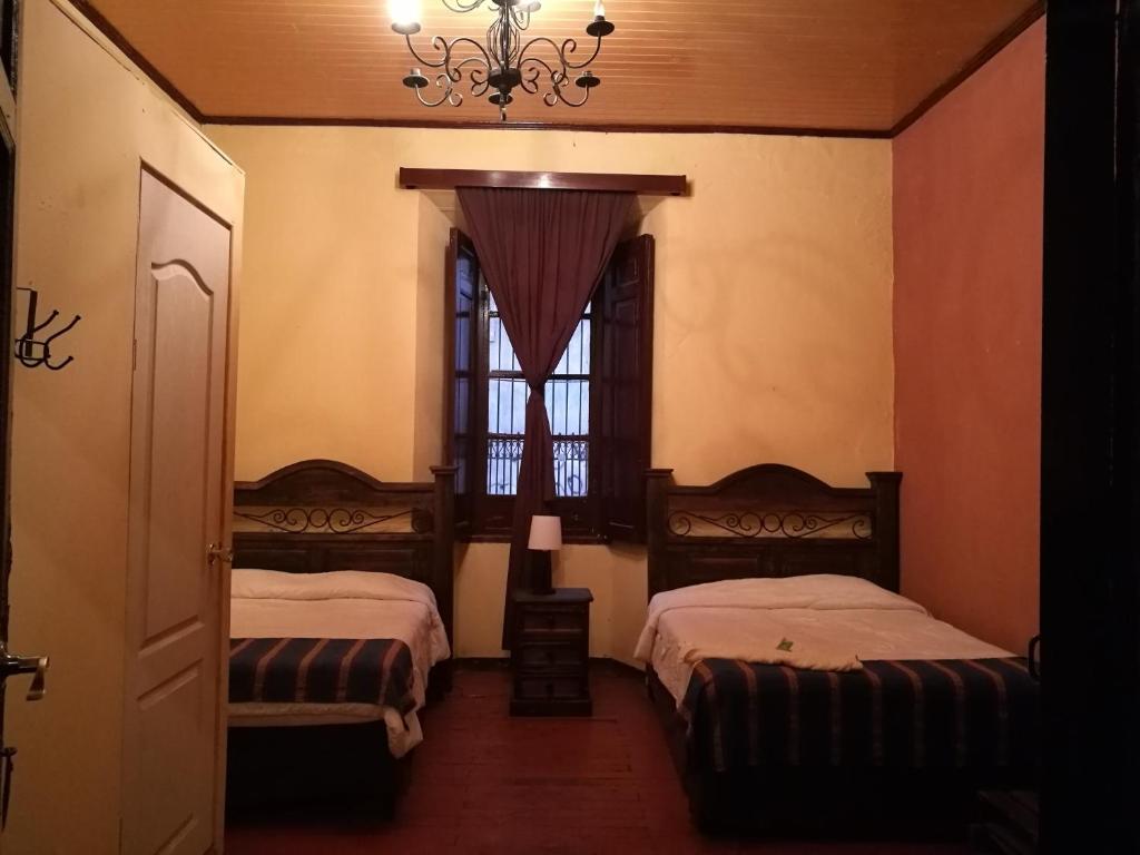 克萨尔特南戈Hotel Casa Quetzaltenango的一间卧室设有两张床和一个带吊灯的窗户。