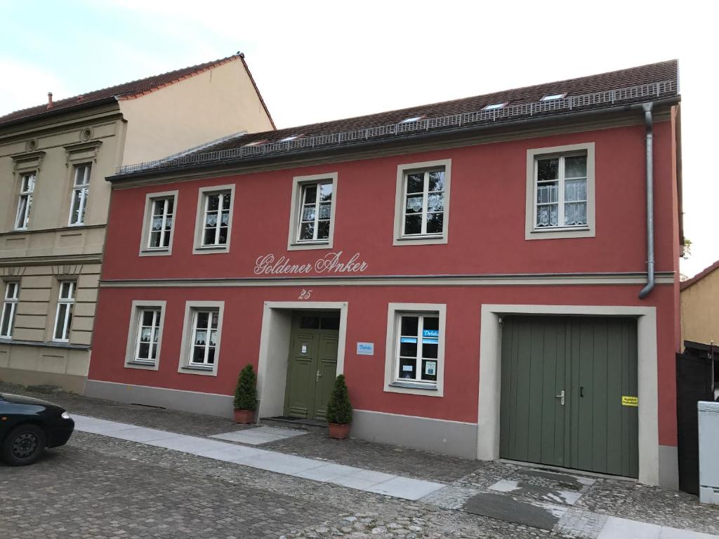 赖因斯贝格Goldener Anker, verschiedene gemütliche Ferienwohnungen的一条街道上带有绿门的红色建筑