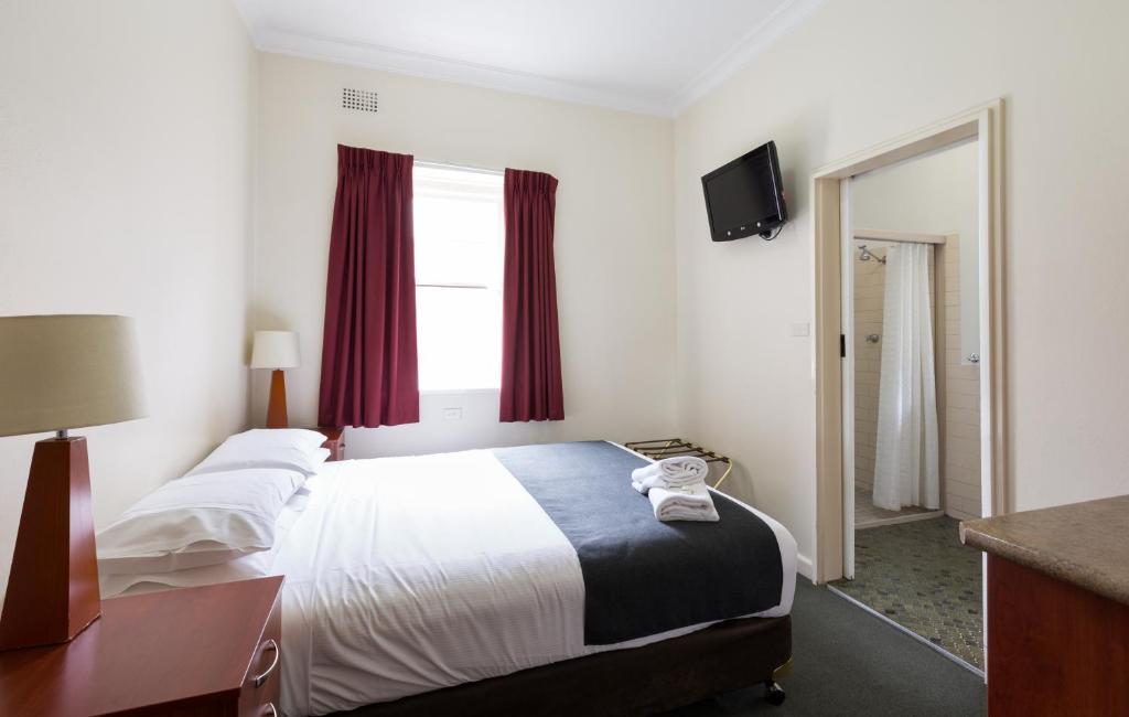 巴瑟斯特Knickerbocker Hotel的酒店客房,设有一张带红色窗帘的大床