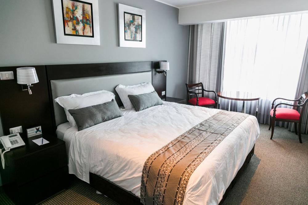 利马Apart Hotel Petit Palace Suites的一间卧室配有一张大床和两个枕头