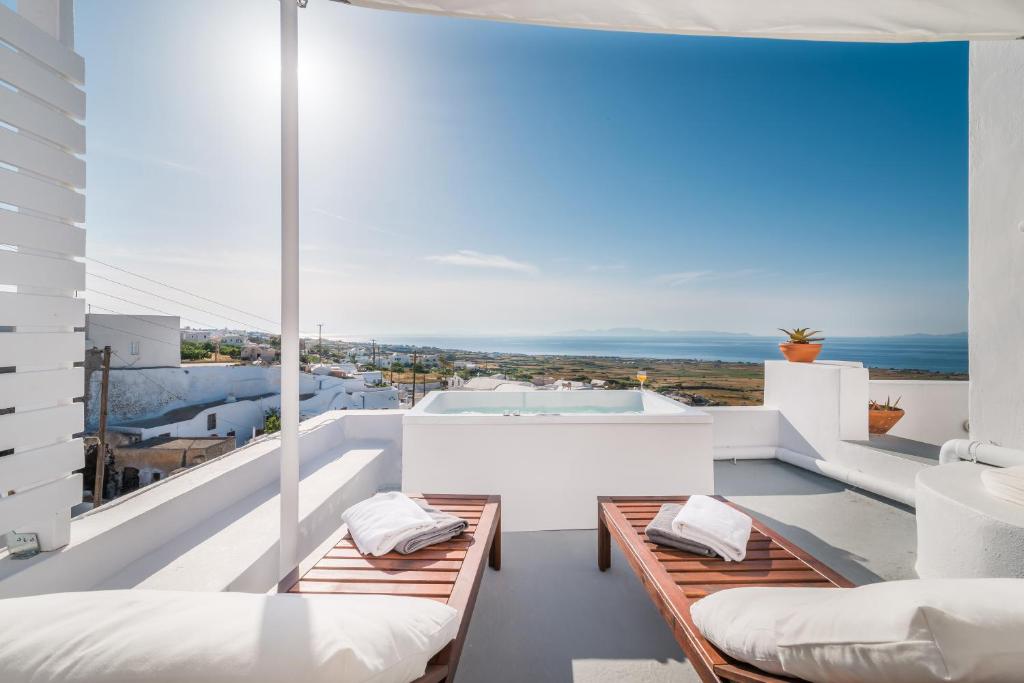 伊亚Fava Eco Suites的阳台配有白色家具,享有海景。