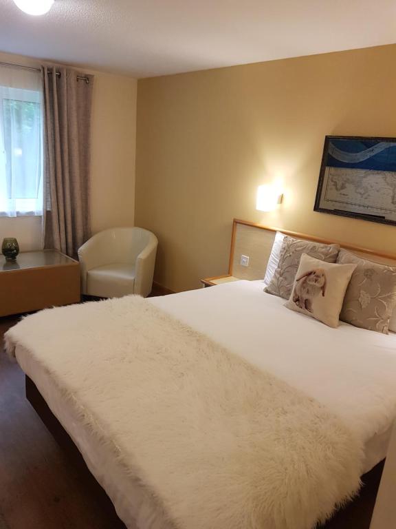 Desborough旅游大酒店的卧室配有一张白色大床和一把椅子