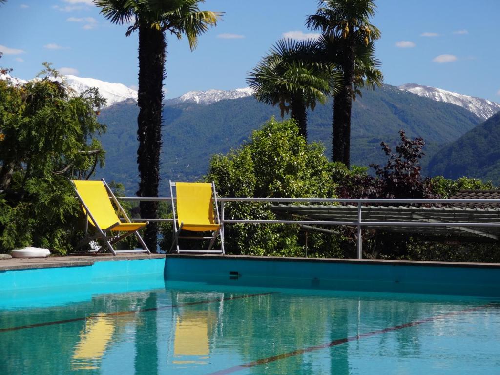洛迦诺天堂度假公寓的两把黄色椅子坐在一个山地游泳池旁
