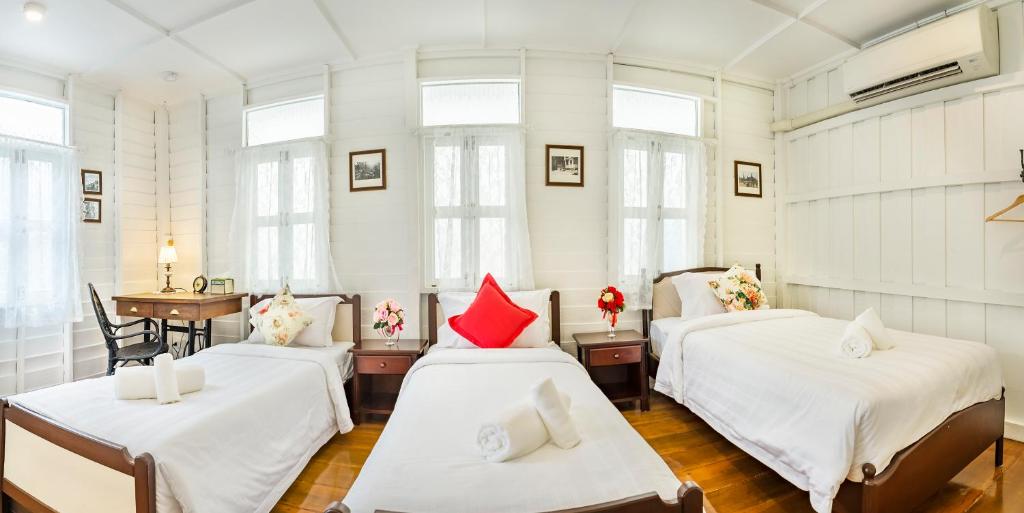 曼谷Baankachitpan Bangkok Hotel的配有白色墙壁和窗户的客房内的三张床