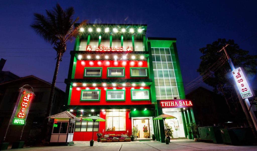 彬乌伦Thiha Bala Hotel的一座红绿的建筑,有灯光