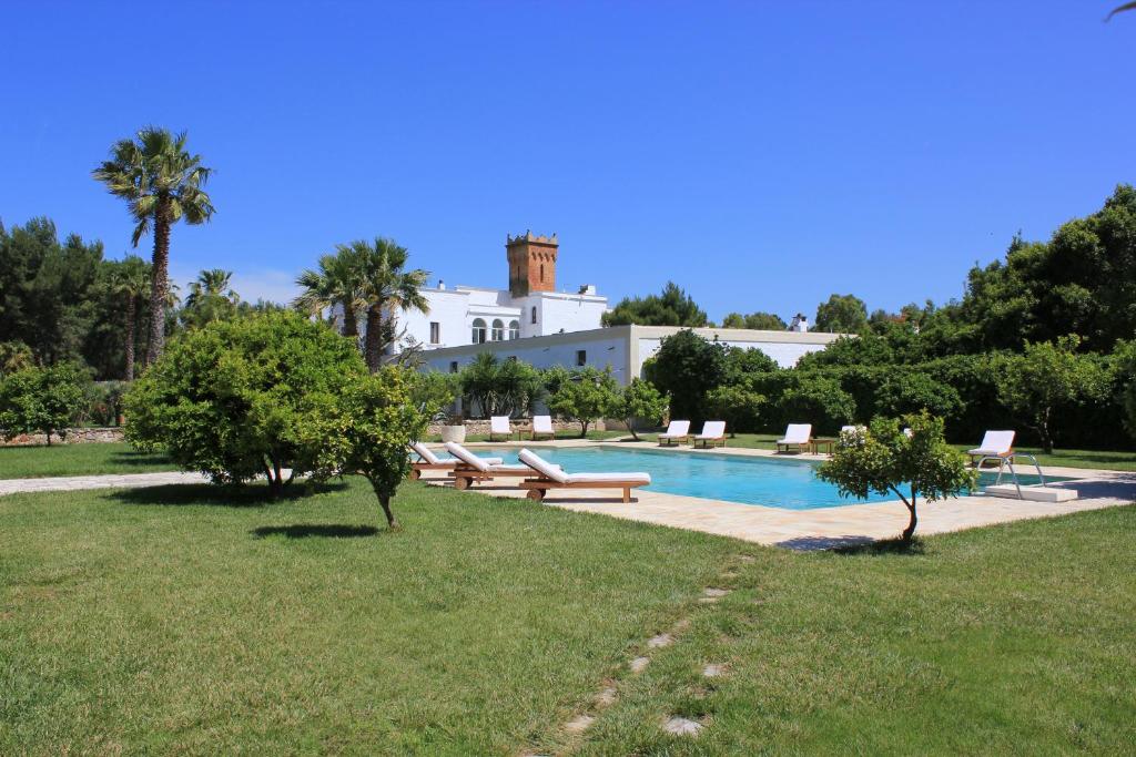 圣维托诺曼玛赛丽亚尹坎特鲁皮酒店的一个带长椅的游泳池和一个位于后面的房子