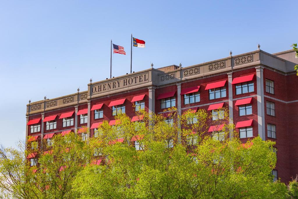 格林斯伯勒O.Henry Hotel的一座红色的建筑,上面有美国国旗