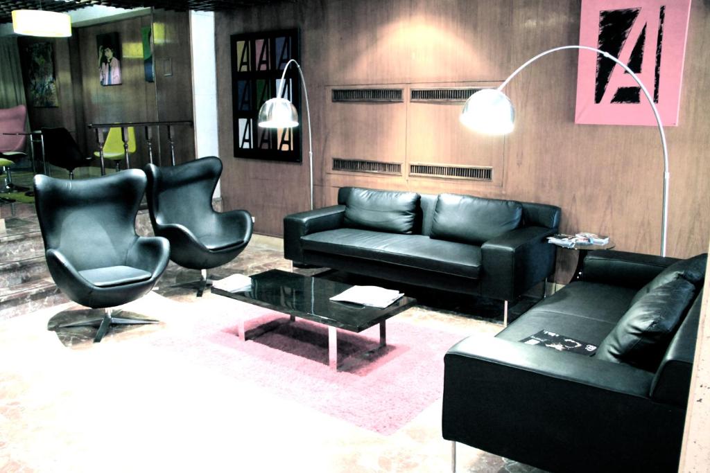 马德里阿纳科酒店的客厅配有黑色皮革家具和桌子
