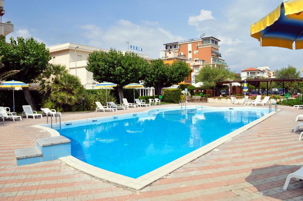 西尼加利亚皮尔拉酒店的酒店的大型游泳池配有椅子和遮阳伞