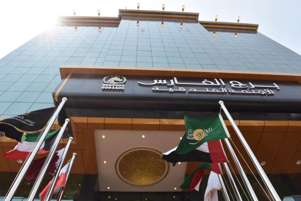 吉达Burj Al Faris Hotel Apartments的挂着旗帜的建筑外墙上的标志