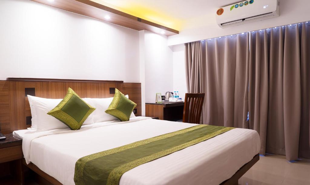 孟买翠布橄榄旅馆的卧室配有带绿色枕头的大型白色床