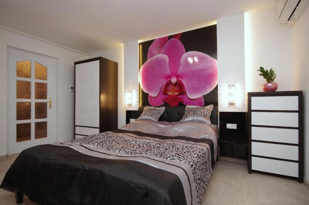 久洛Regina Delux Apartman的卧室的墙上挂着一朵粉红色的大花