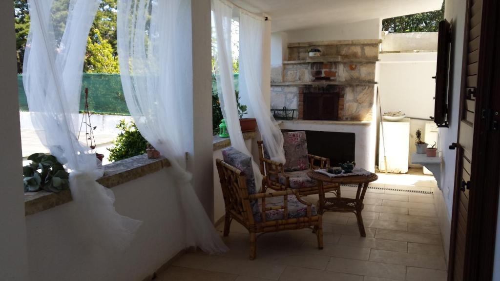 奥斯图尼Villa Gardenia的客房设有两把椅子和带窗帘的壁炉