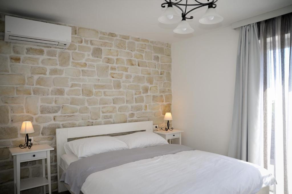 班约勒APP Rab Banjol 217的卧室配有白色的床和石墙