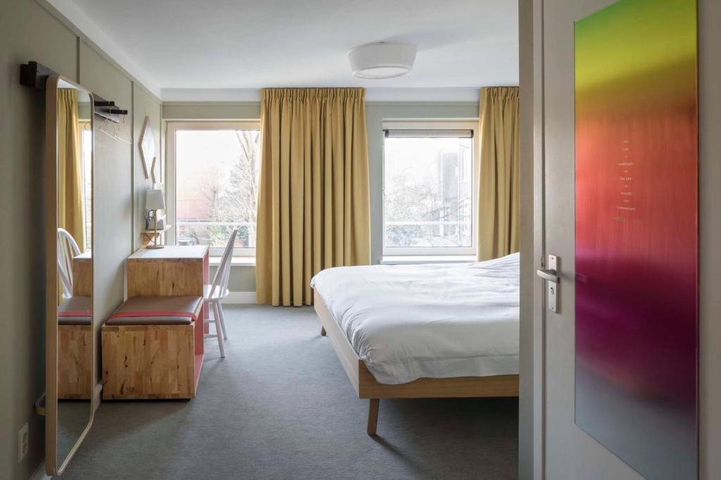 鹿特丹照明酒店的一间卧室配有一张床、一张书桌和一个窗户。