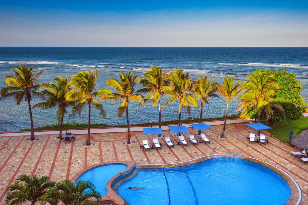 达累斯萨拉姆海边悬崖酒店的一个带椅子和棕榈树的游泳池以及大海