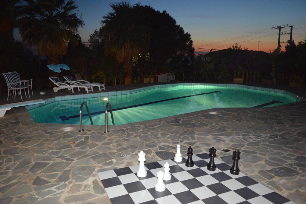 拉格尼西Villa Suites Lagonisi Luxury的游泳池前的国际象棋棋盘