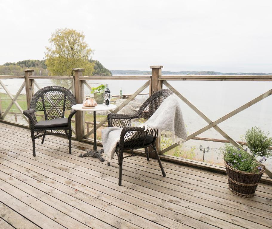 卢恩斯基尔Anfasteröd Gårdsvik - Badstugorna的一个带三把椅子和一张桌子的甲板,享有水景