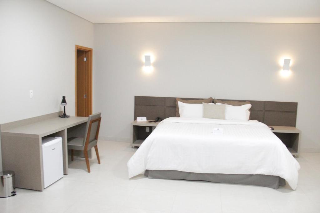 MineirosGran Park Hotel e Convenções的卧室配有一张白色大床和一张书桌