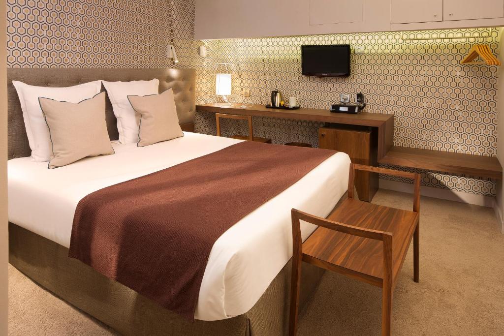 巴黎索菲杰曼酒店的一间卧室配有一张床、一张书桌和一台电视