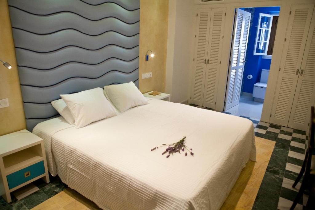 科尼尔-德拉弗龙特拉Hostal El Alojado de Velarde的卧室配有白色的床,床上有花