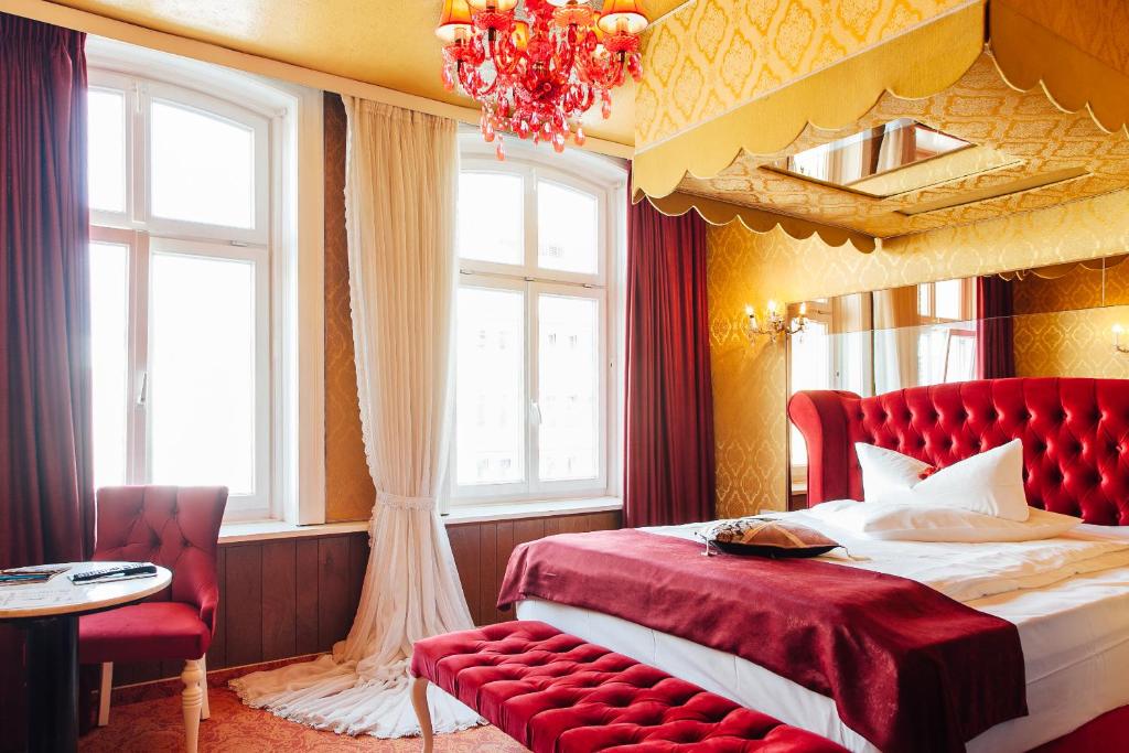 汉堡山村酒店的一间卧室配有一张红色的床和吊灯。