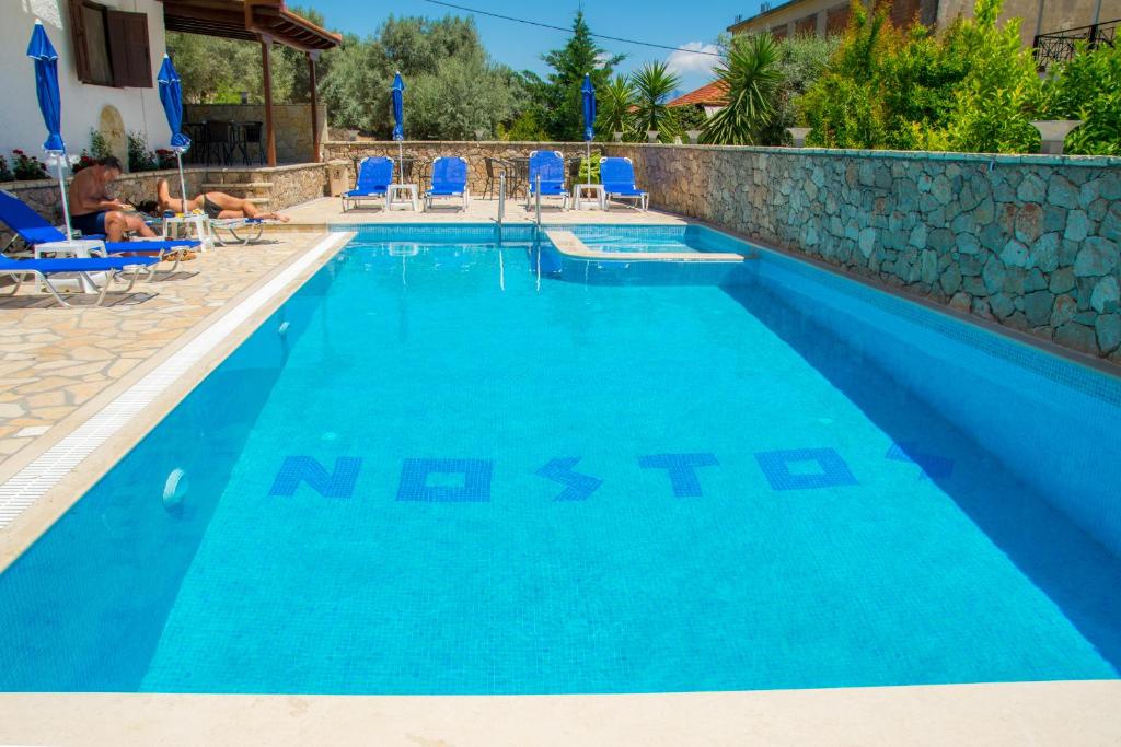 奈德里Hotel Nostos的一个带蓝色椅子的度假村的游泳池