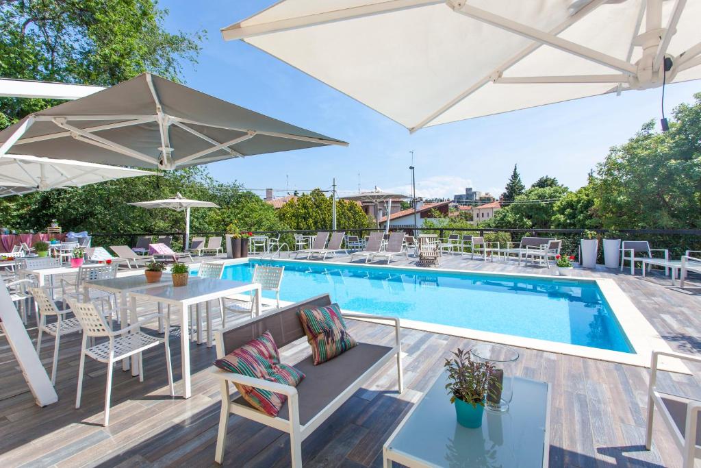 杜伊诺博尔戈杜伊诺别墅酒店的庭院内一个带桌子和遮阳伞的游泳池