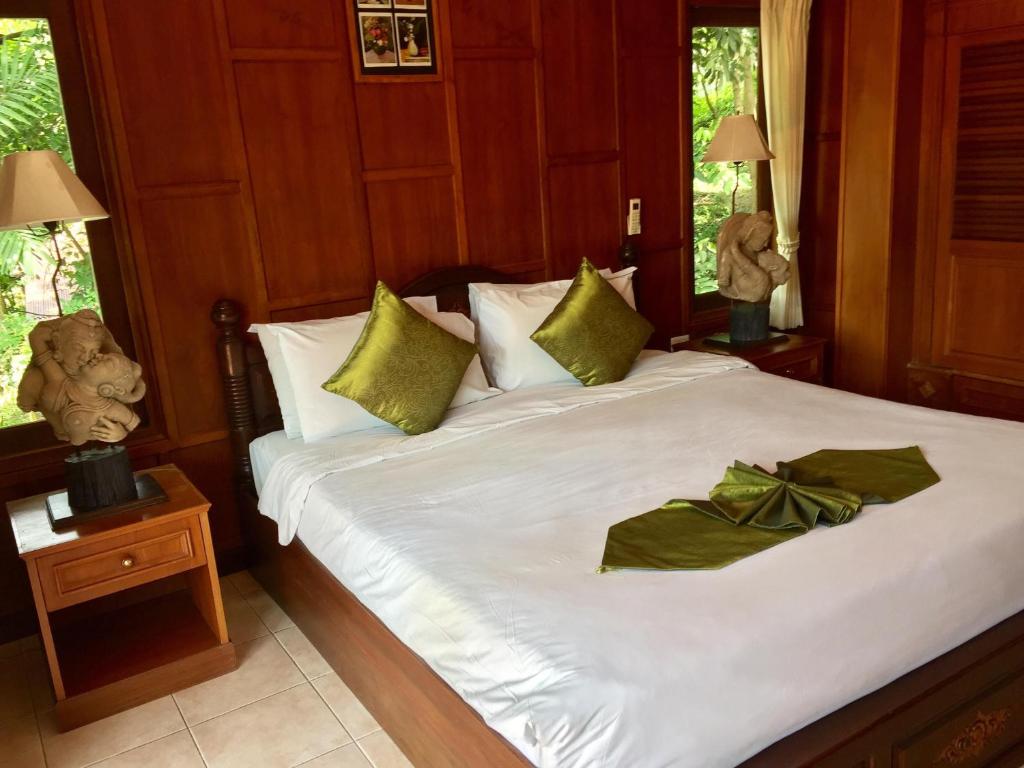 湄南海滩班拉加河内别墅酒店的一间卧室,配有一张带绿弓的床